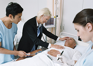 Three healthcare providers at man’s hospital bedside. 