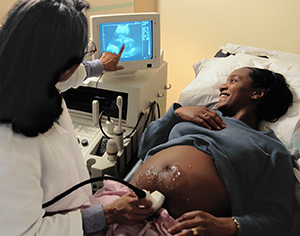 Healthcare provider performing ultrasound on pregnant woman.
