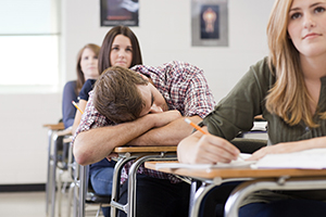 Young male student sleeping at his desk.